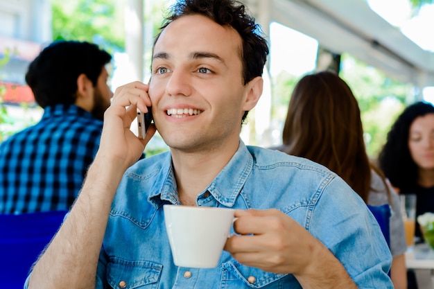 Mann, der Handy verwendet und Kaffee trinkt