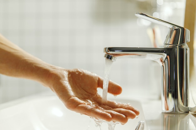 Mann, der ihre Hand im Badezimmer wäscht und reinigt.