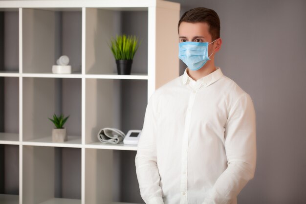 Mann, der im Büro arbeitet und eine Maske zum Schutz vor Coronavirus trägt