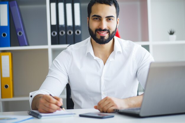 Mann, der im Büro vor Tischrechner arbeitet