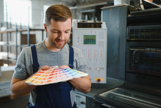 Foto mann, der im druckhaus mit papier und farben arbeitet
