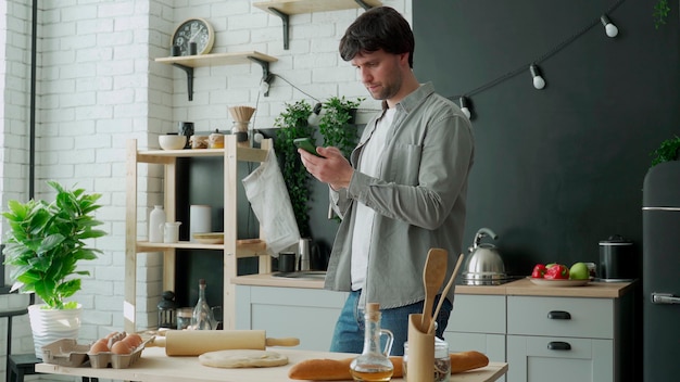 Mann, der im Internet mit Telefon steht, das in der Küche steht