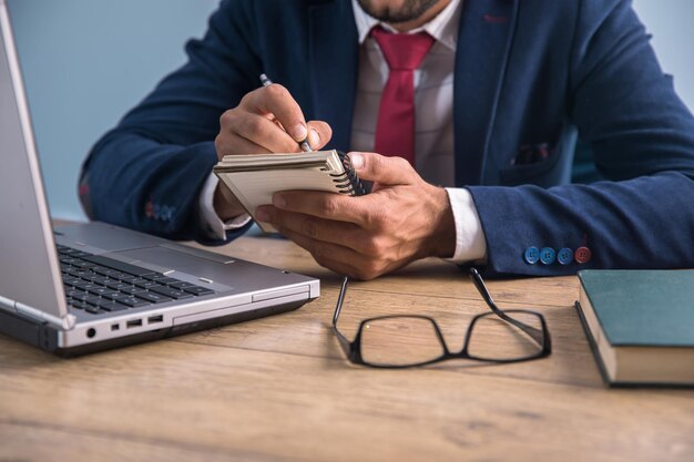 Mann, der im Notizblock und am Computer arbeitet