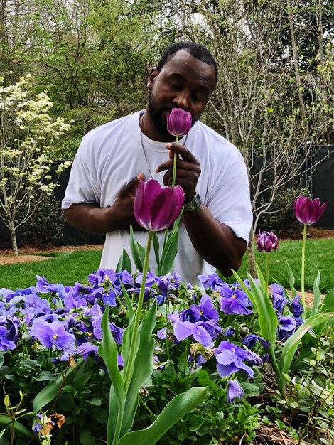 Foto mann, der im park magenta-tulpen riecht