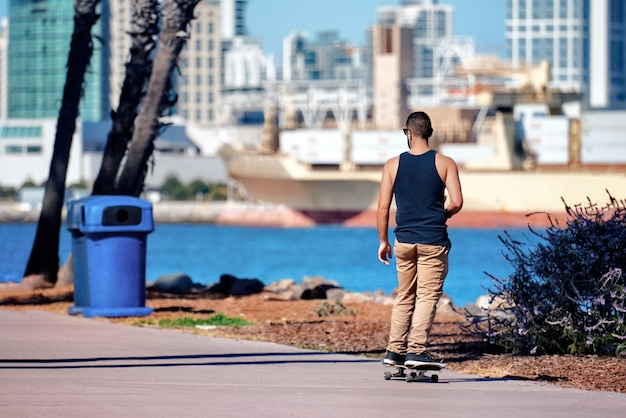 Mann, der im Park mit Meer und Stadt San Diego skatet