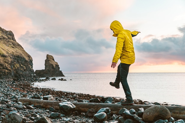 Foto mann, der in der waage über einem baumstamm am meer in schottland hängt