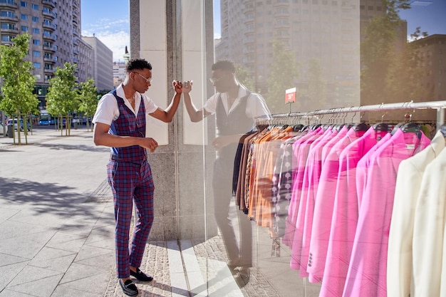 Mann, der in einem Kleidungsgeschäft Schaufenster Einkaufszeit sucht