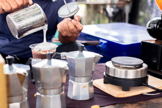 Mann, der Kaffee aus der Moka-Kaffeemaschine in eine Kaffeetasse gießt Hand mit italienischer klassischer Moka-Kanne, die Kaffee im Vintage-Kaffee-Stil gießt