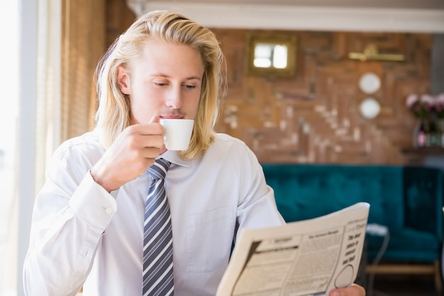 Foto mann, der kaffee beim lesen der zeitung trinkt