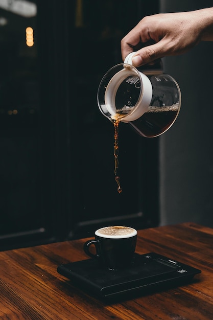 Mann, der Kaffee in eine Tasse auf den Tisch gießt