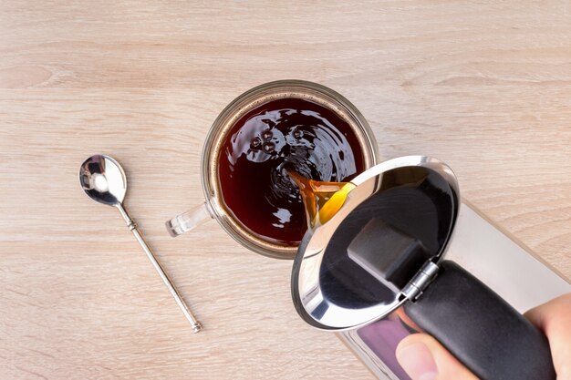 Mann, der Kaffee in Tasse auf Holztisch gießt.