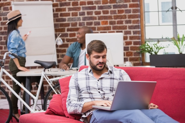 Mann, der Laptop auf Couch im Büro verwendet