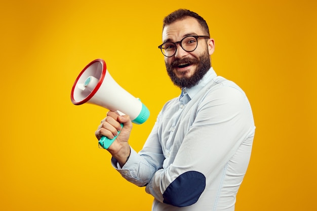 Mann, der Megaphon hält und lächelt, während er isoliert über Gelb steht