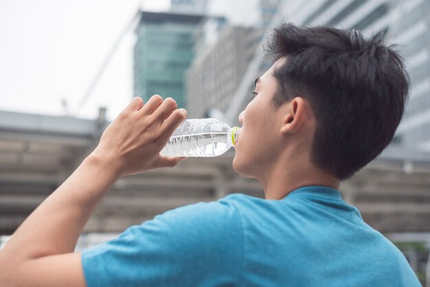 Mann, der Mineralwasser trinkt, nachdem Übung beendet ist