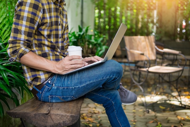 Mann, der mit einem Laptop in einem Garten arbeitet