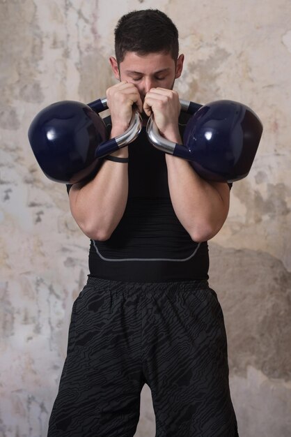 Mann, der mit Kettle Bell trainiert und Muskeln anspannt Muskulöser athletischer Bodybuilder Fitness Model Übungen