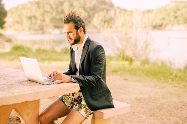 Mann, der mit Laptop gegen malerische Landschaft arbeitet