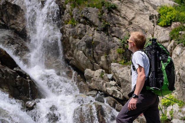 Mann, der mit Rucksack wandert und Wasserfall betrachtet Porträt eines männlichen Erwachsenen, der im Freien steht