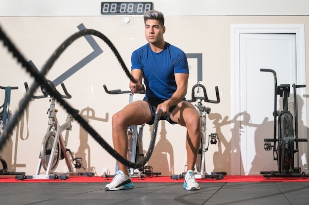 Mann, der mit Seil im Fitness-Studio für funktionelles Training trainiert