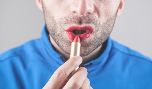 Mann, der roten Lippenstift auf Lippen anwendet.