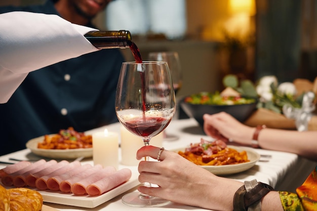 Mann, der Rotwein in ein Weinglas gießt