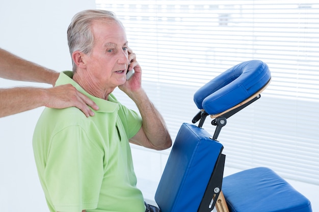 Foto mann, der rückenmassage bei der unterhaltung am telefon hat