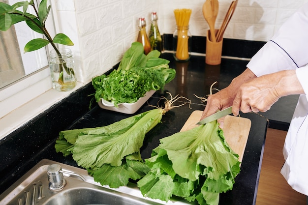 Mann, der Salatwurzeln abschneidet