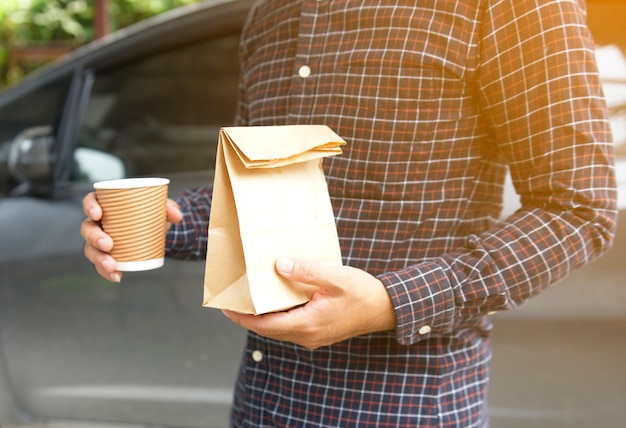 Mann, der Schalenkaffee und -brot in der Papiertüte hält.