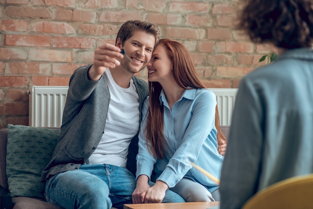 Mann, der Schlüssel zum neuen Haus und zur glücklichen Frau zeigt