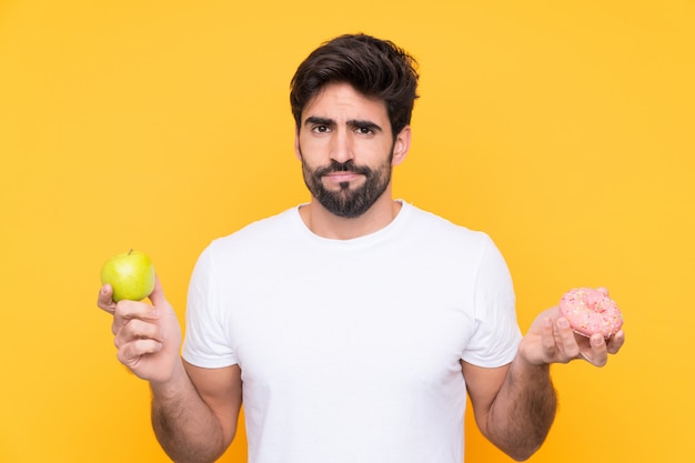 Mann, der Schokolade und Donut über lokalisierter Wand hält