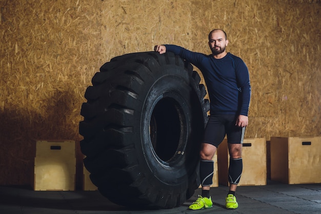 Mann, der schweren Reifen im Fitnessstudio umdreht.