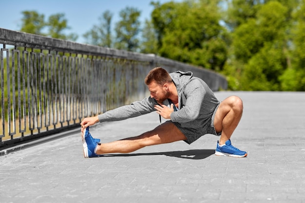 Mann, der sein Bein auf der Brücke streckt