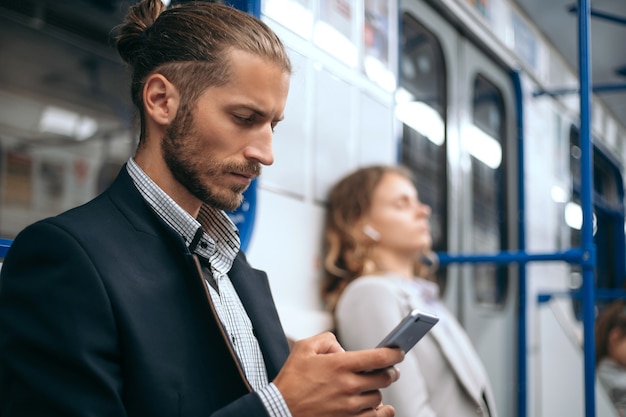 Mann, der sein Smartphone benutzt, während er in der Zug-U-Bahn sitzt