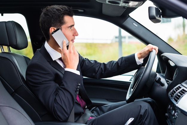 Mann, der sein Telefon beim Autofahren verwendet