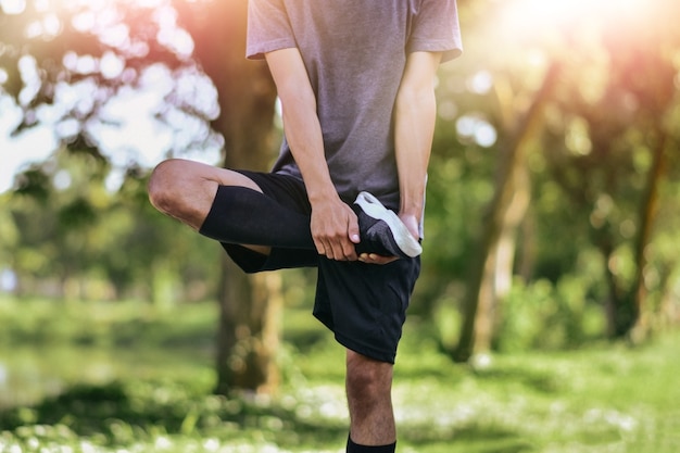 Mann, der seine Beinmuskeln vor dem Training ausdehnt, Junges männliches Joggersportlertraining