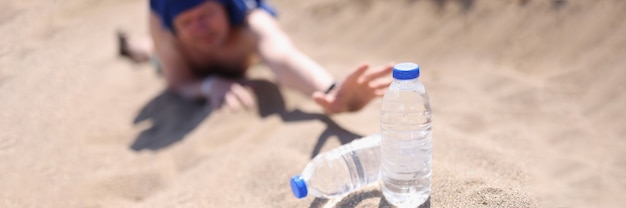 Mann, der seine Hände mit Plastikflasche Wasser in Wüstennahaufnahme ausdehnt