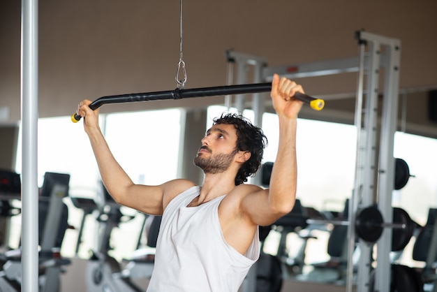 Mann, der seine Schultern und zurück in einem Fitnessstudio trainiert