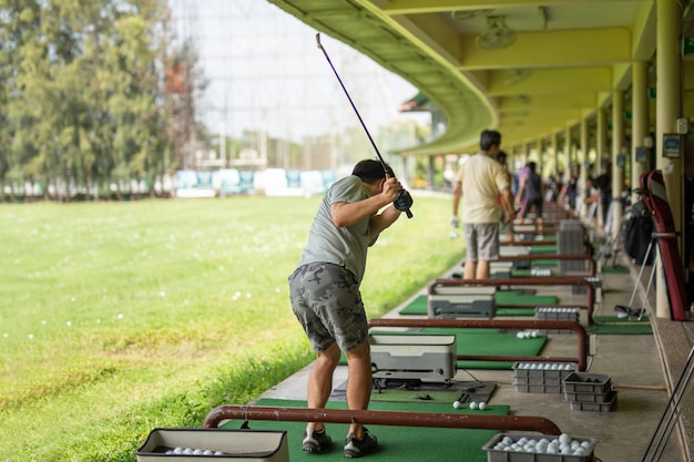 Mann, der seinen Golfschwung am Golf Driving Range übt.