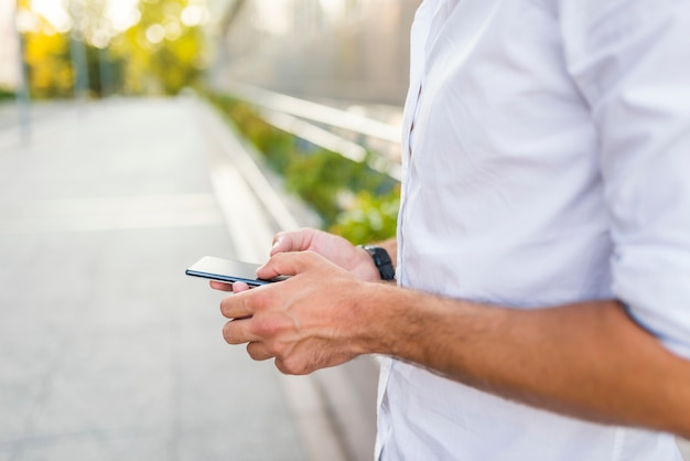 Mann, der seinen Handy auf der Straße verwendet