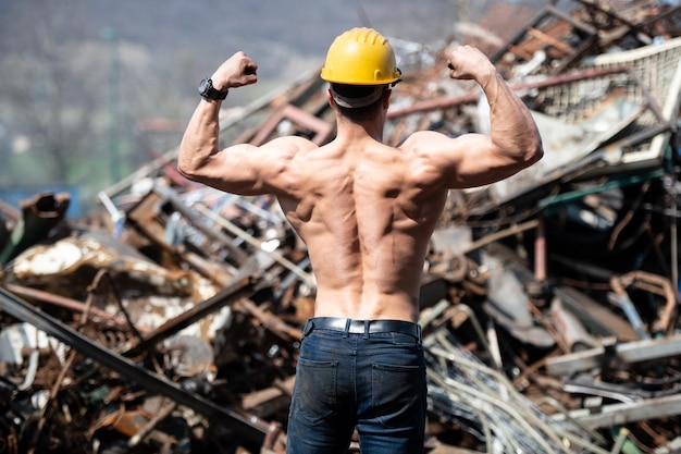 Mann, der seinen Körper im industriellen Schrottplatz zeigt