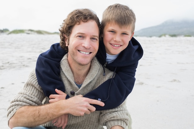 Mann, der seinen Sohn am Strand huckepack trägt