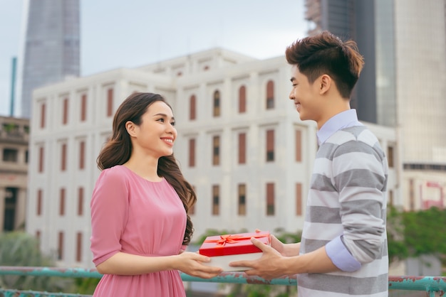Mann, der seiner Frau ein Geschenk gibt. Asiatisches Paar verliebt im Freien
