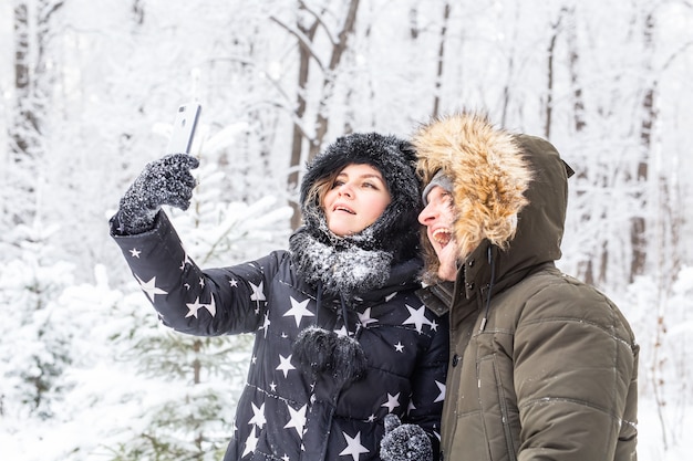Mann, der selfie foto macht junges romantisches paar lächeln schneewald im freien winter.