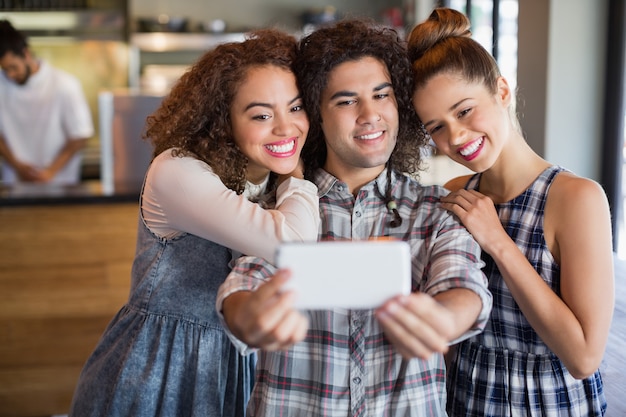 Mann, der selfie mit Freundinnen im Café nimmt