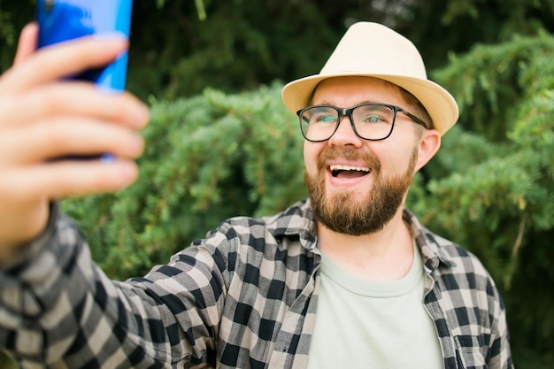 Mann, der selfie-porträt über baumhintergrund macht, glücklicher tausendjähriger kerl, der sommerferien in ci genießt