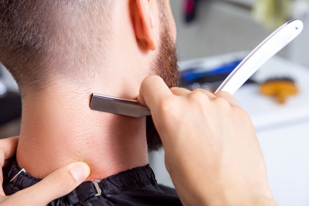 Mann, der sich im Friseursalon rasiert.