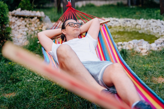 Foto mann, der sich in der hängeschleife im garten entspannt