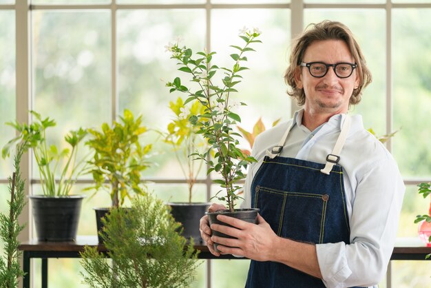 Mann, der sich zu Hause um ihre Topfpflanzen kümmert, im Garten arbeitet und zu Hause pflanzt