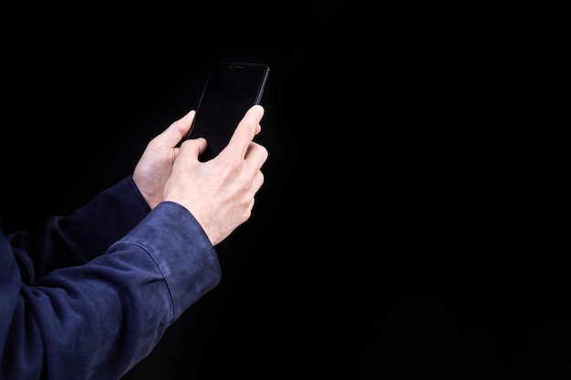 Mann, der Smartphone-Bildschirm auf dunklem Hintergrund betrachtet