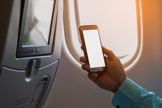 Mann, der Smartphone mit leerem Bildschirm auf einem Flugzeug nahe Fenster verwendet